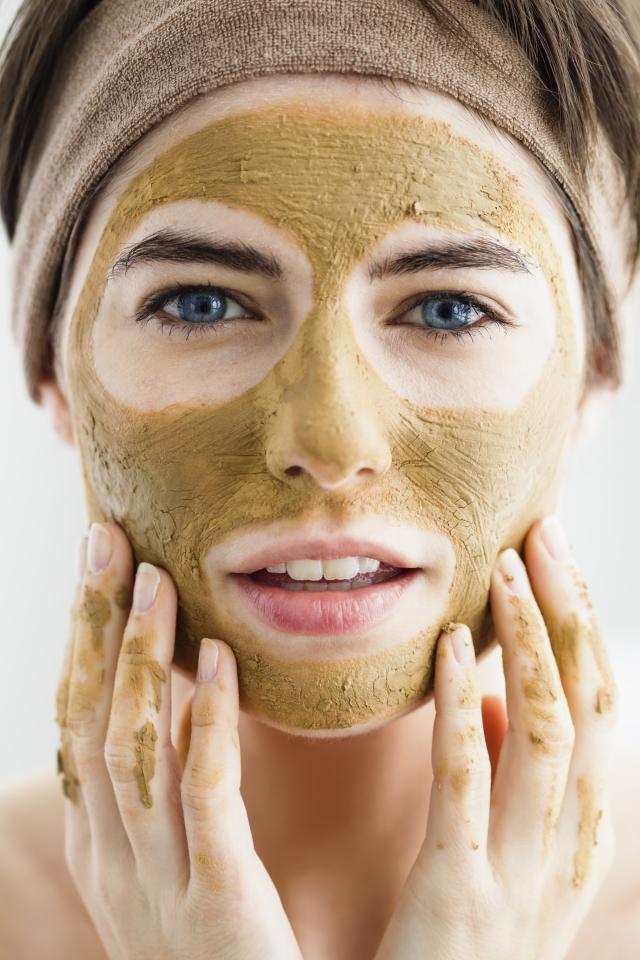 Germany, Bavaria, Munich, Portrait of young woman with clay mask, close up